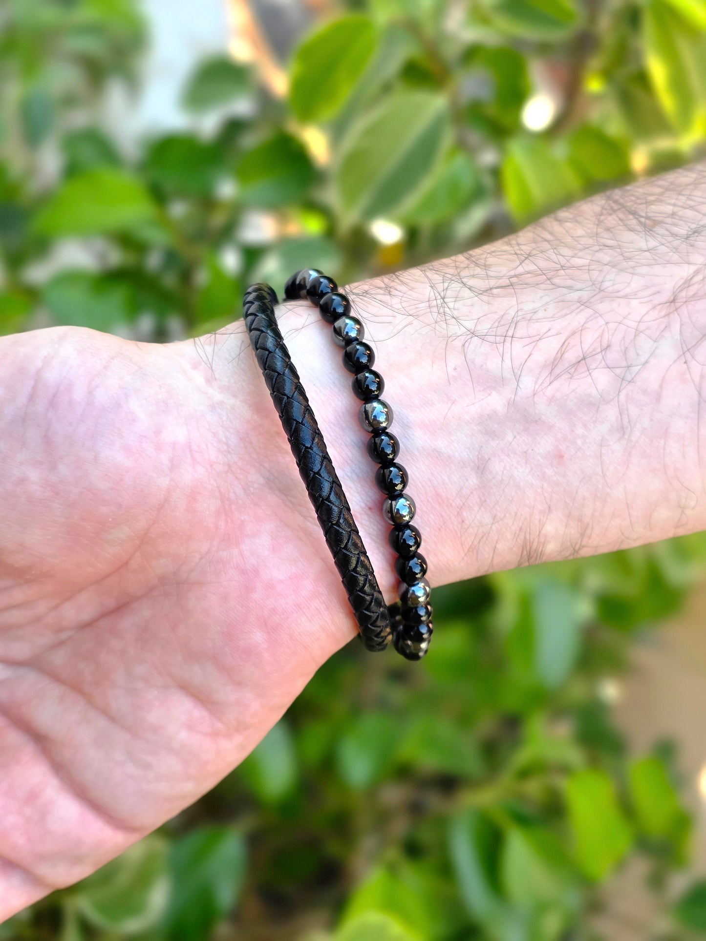 Detalle de pulsera de cuero negro con perlas de hematite y ónix, montada en acero inoxidable