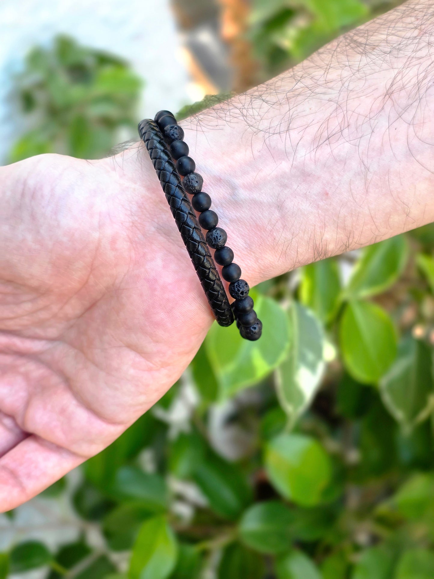 Detalle de pulsera de cuero negro con perlas de lava y shungita, montada en acero inoxidable