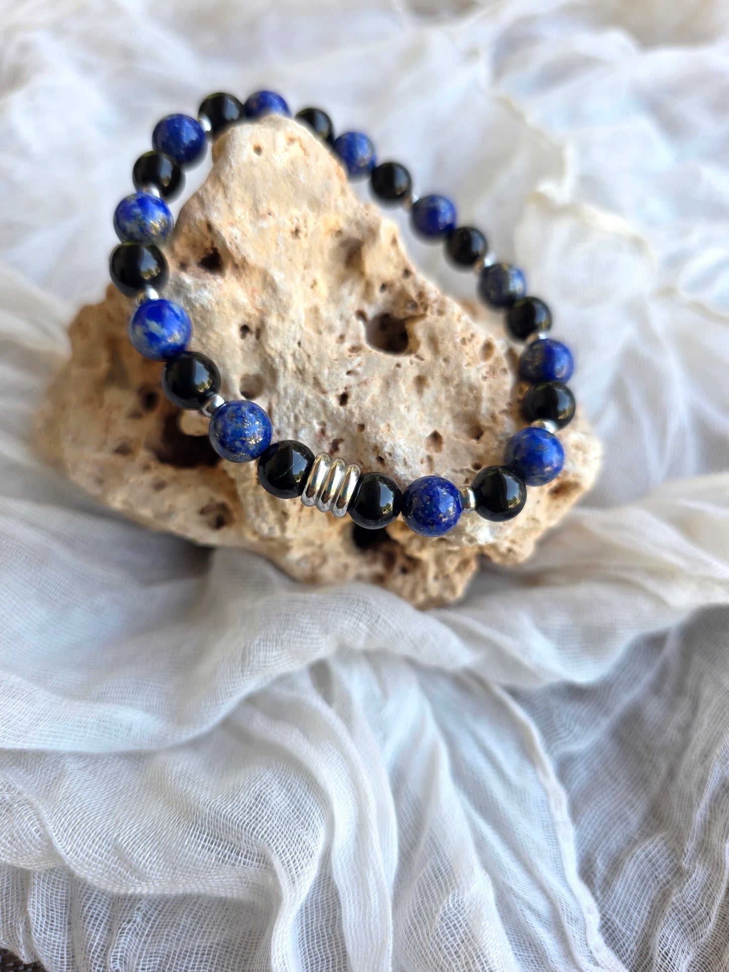 Detalle de pulsera plateada con perlas de lapislázuli y ónix en acero inoxidable