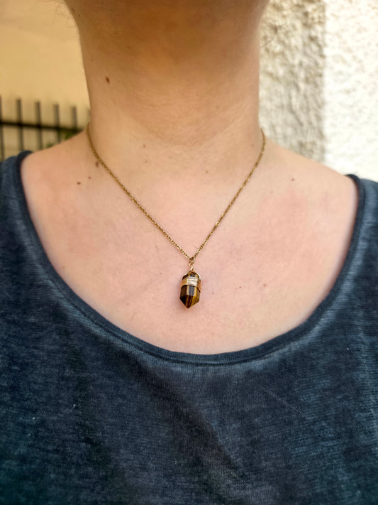 Detalle de colgante de ojo de tigre biterminada en acero inoxidable bañado en oro