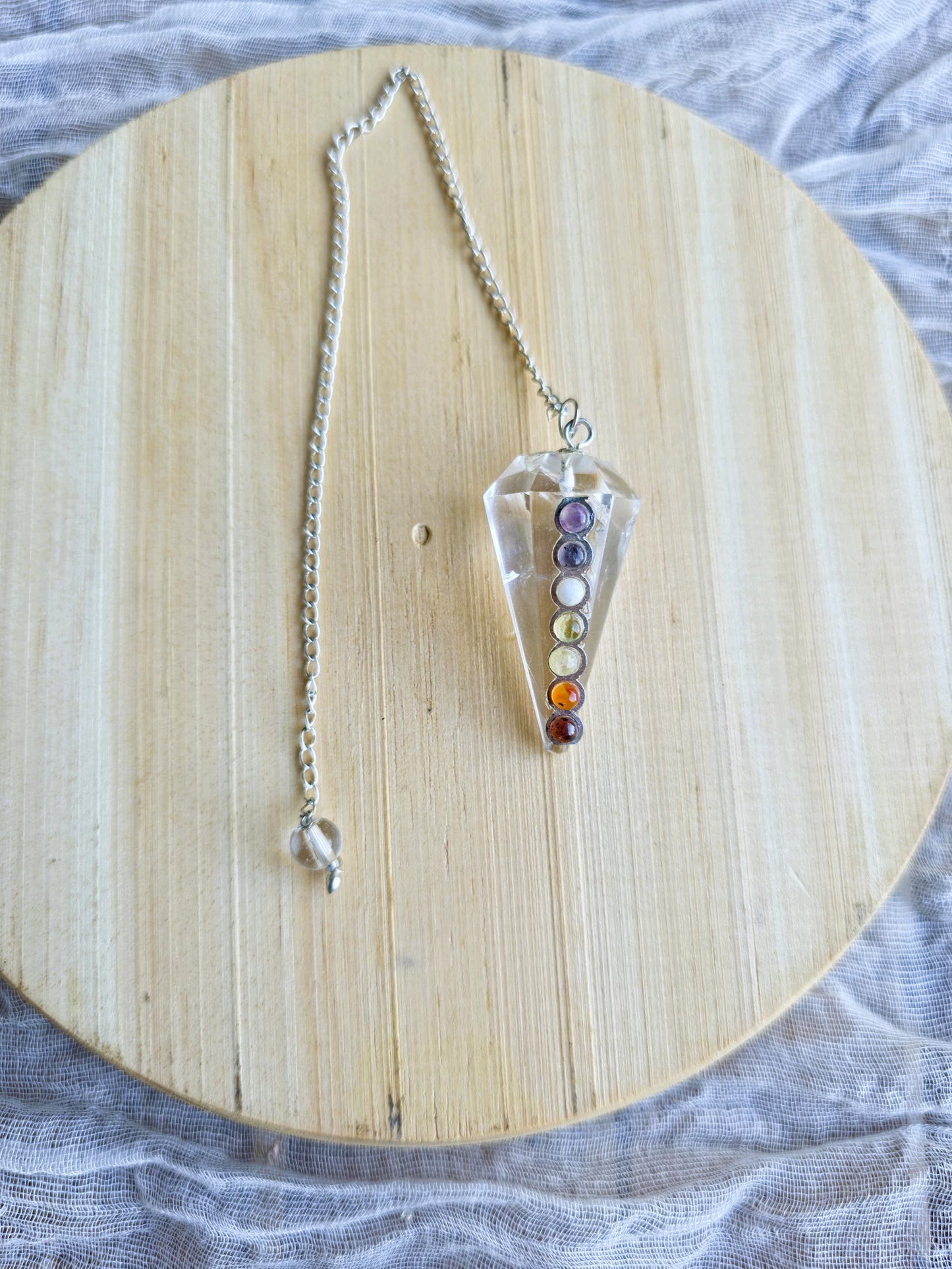 péndulo cuarzo cristal 7 chakras sobre fondo blanco