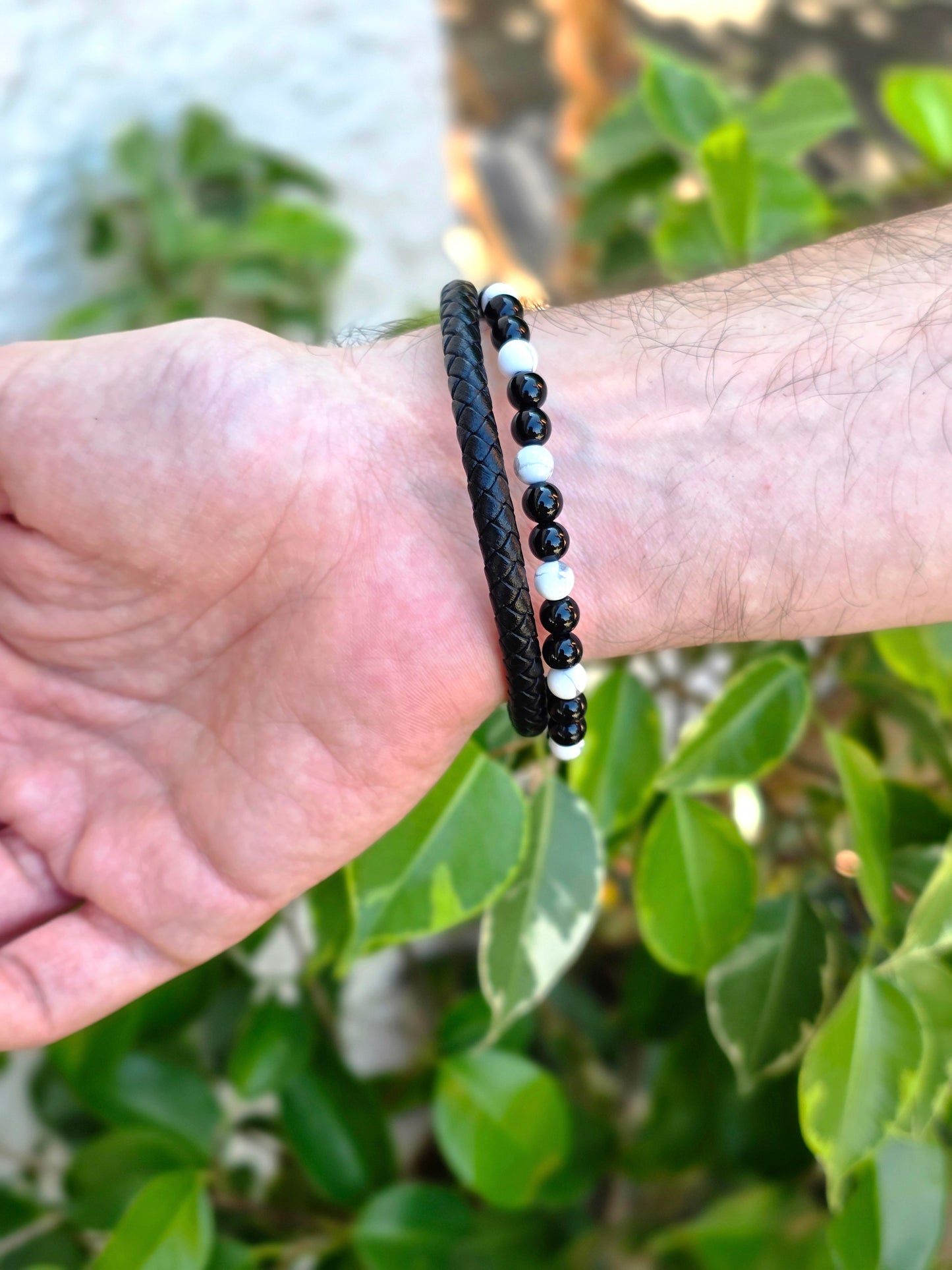 Detalle de pulsera de cuero negro con perlas de howlita y ónix, montada en acero inoxidable